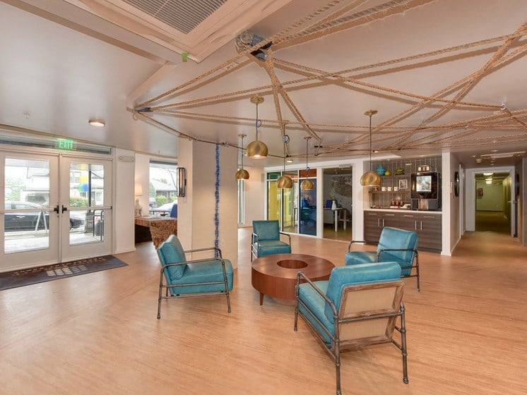 Leasing Office with Hardwood Inspired Floor, Blue Sofa Chairs, Hanging Ceiling Lights and Exit Door